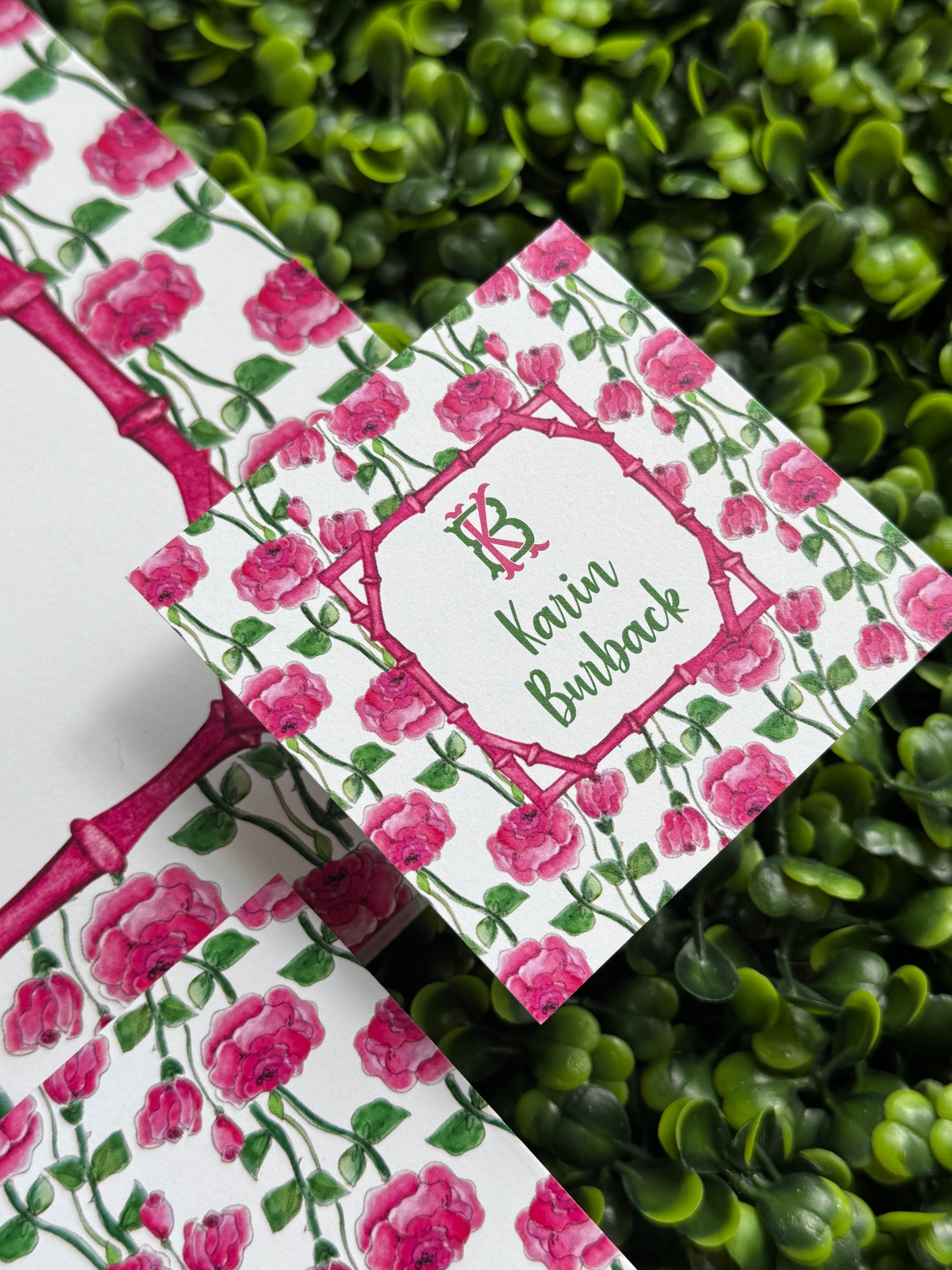 Floral calling card with pink roses on a white background, placed on green foliage.
